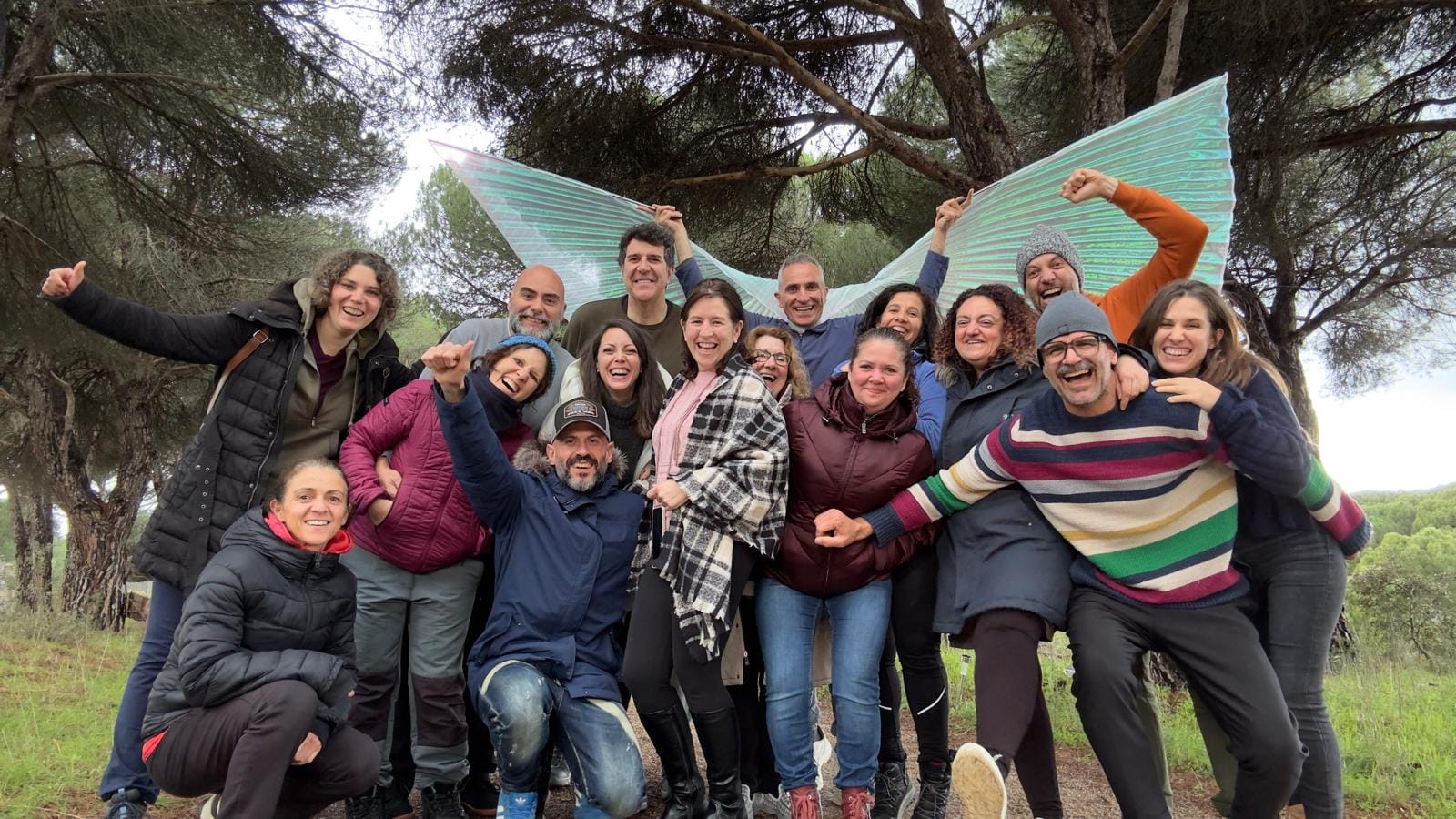 grupo de personas mirandose y abrazandose con cariño en un taller de crecimiento personal en una carpa en la naturaleza