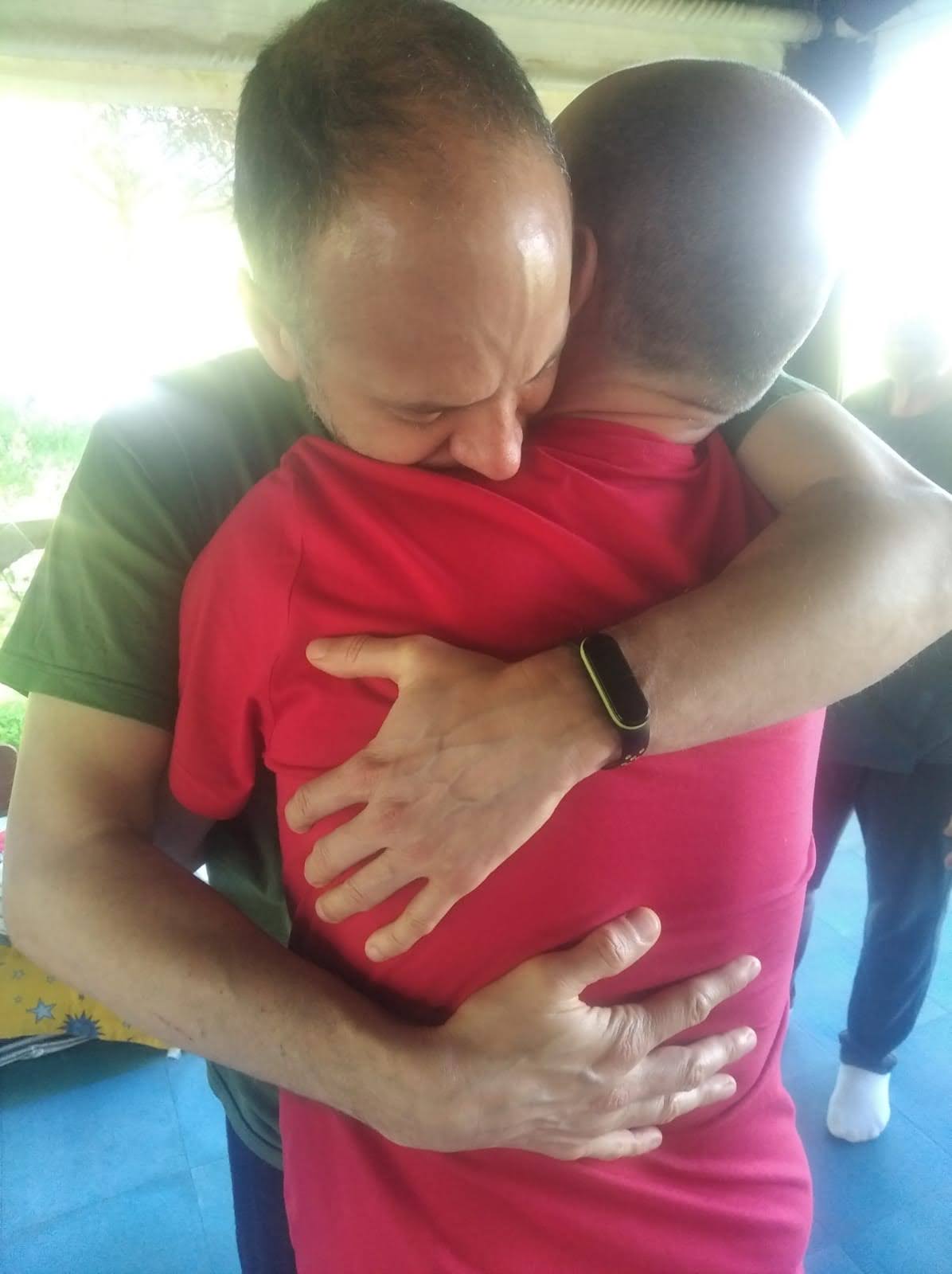 grupo de personas mirandose y abrazandose con cariño en un taller de crecimiento personal en una carpa en la naturaleza