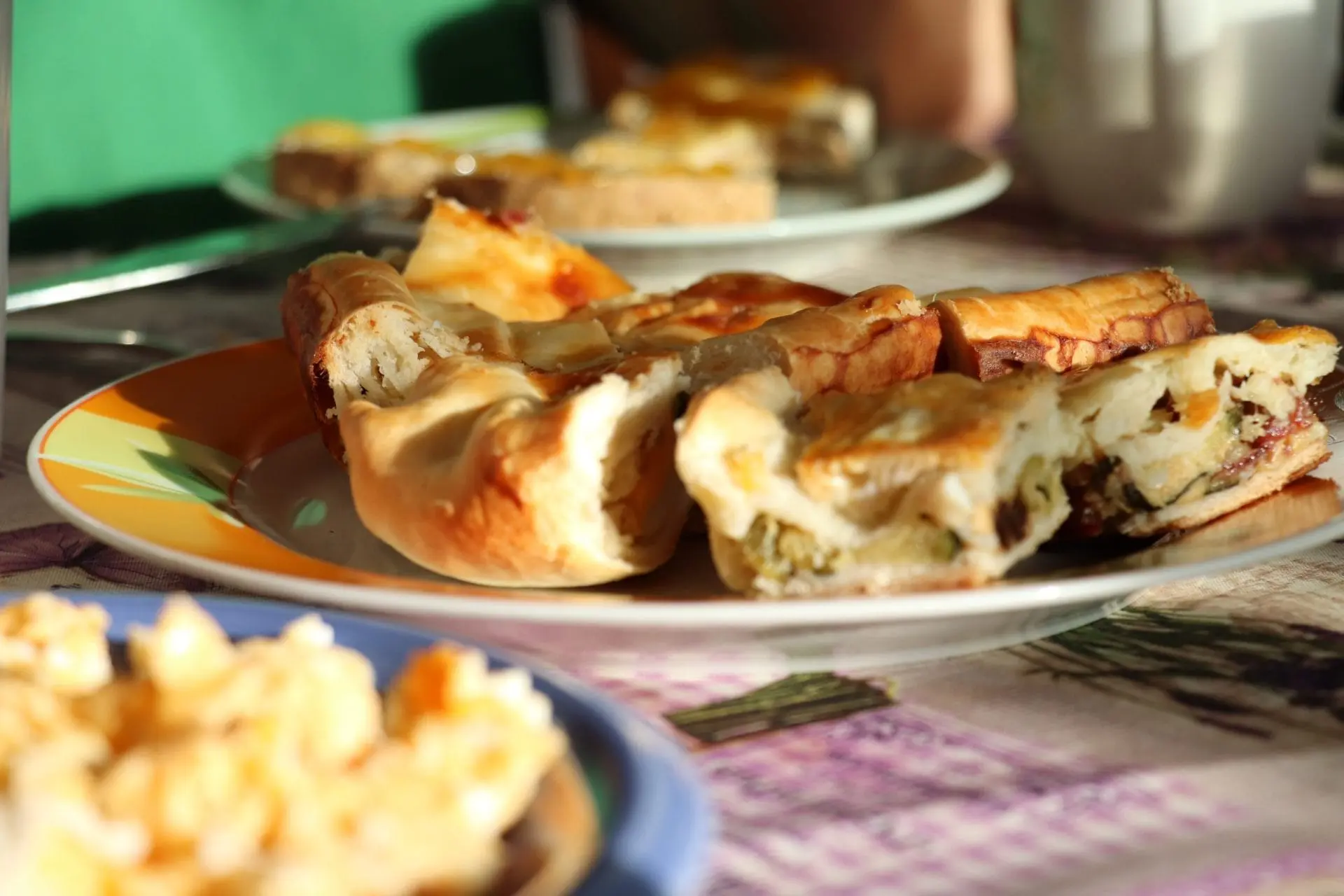 empanada-scaled.jpg círculo con cojines de colres en un espacio con un suelo con colores y detras arboles verdes